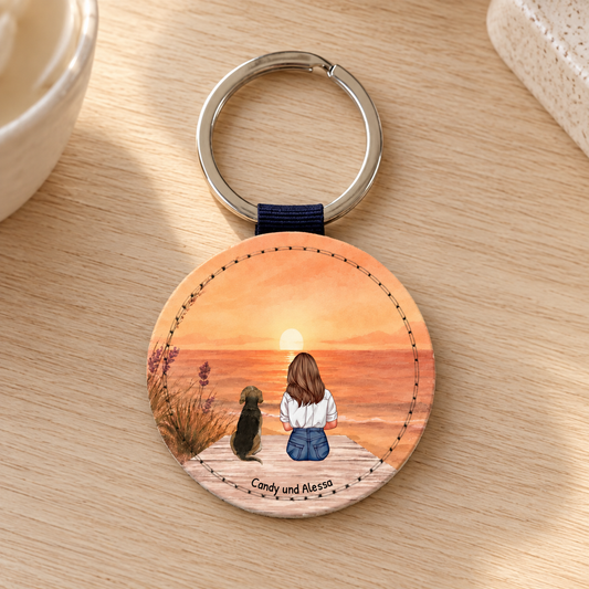 Personalized round keychain with an illustration of a woman and a dog at sunset.
