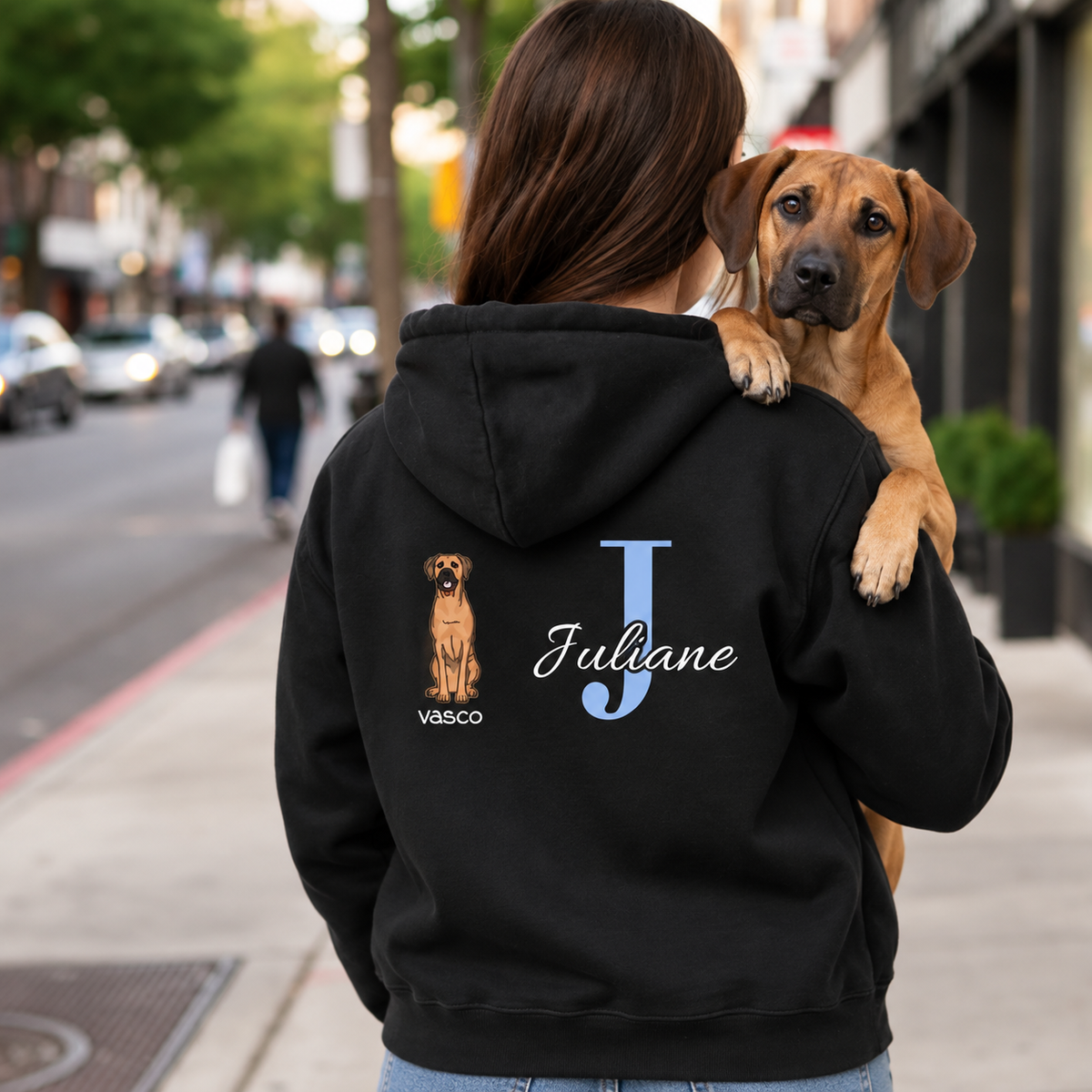 Black hoodie with personalized initial "J" and dog motif on the back. Worn by a person with a dog.