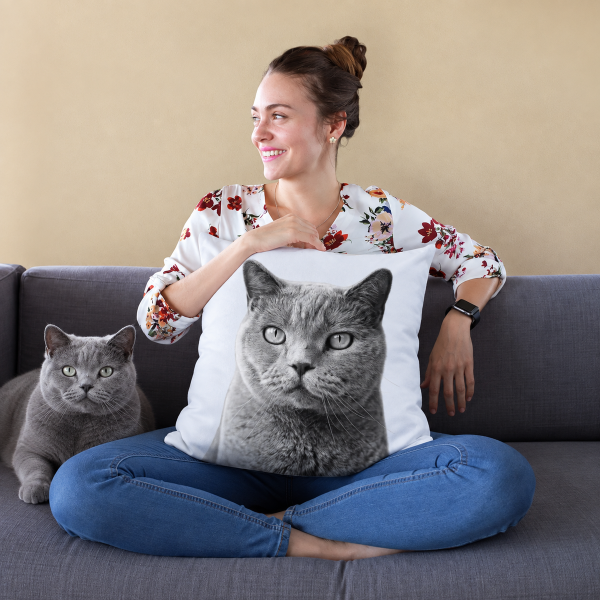 Pillow with a black-and-white cat portrait, person sitting on a sofa holding the pillow.