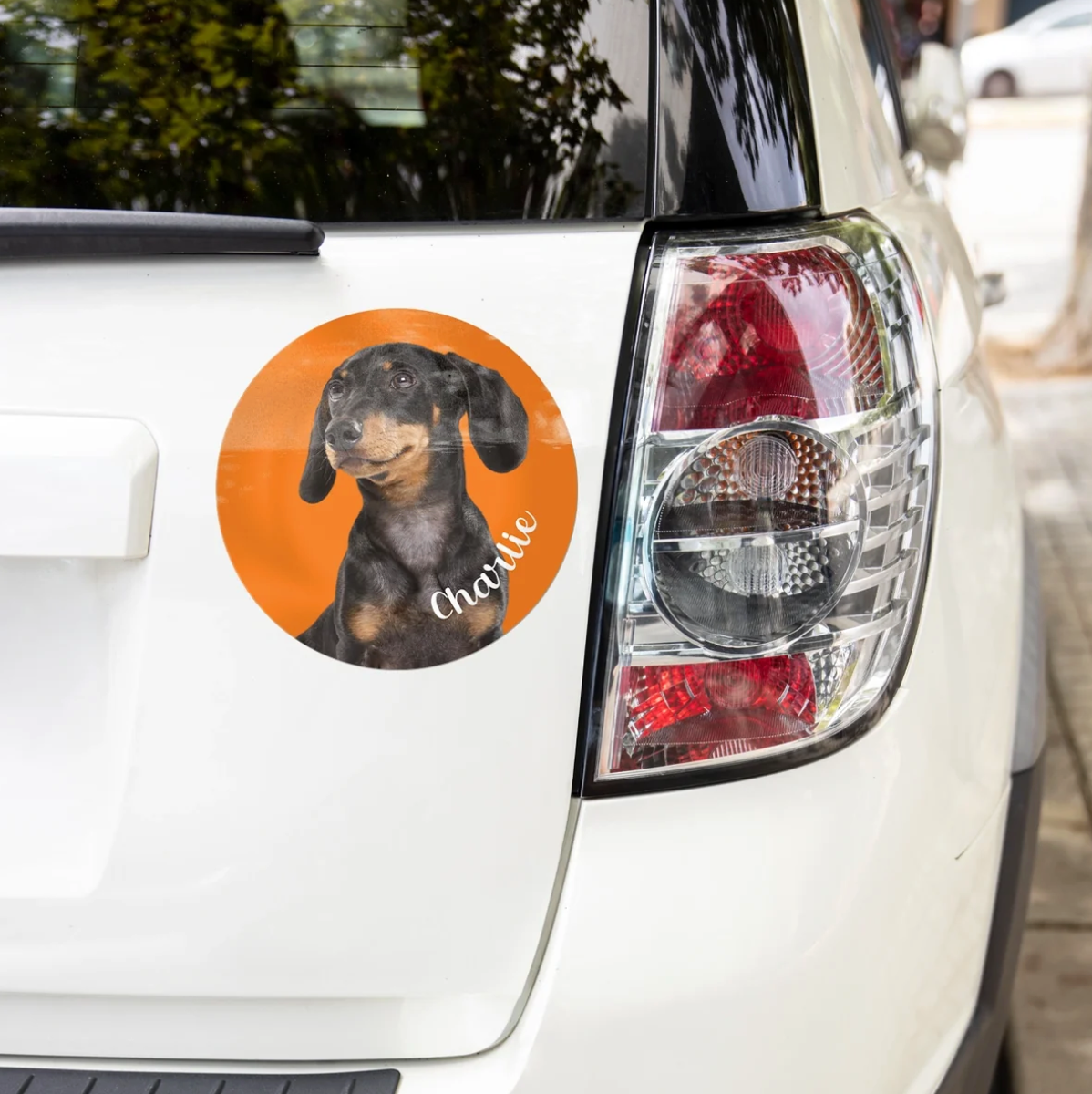 Personalized car sticker with a picture of a dachshund on an orange background, applied to a white car.