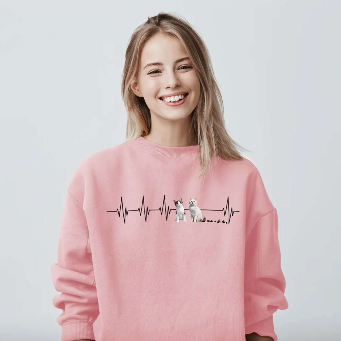Pink sweatshirt with heartbeat design and animal illustrations. The wearer is smiling.