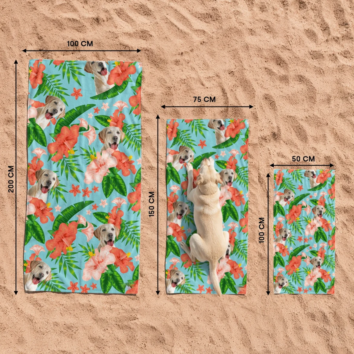 Three personalized beach towels with dog motif and colourful flowers on sandy ground.