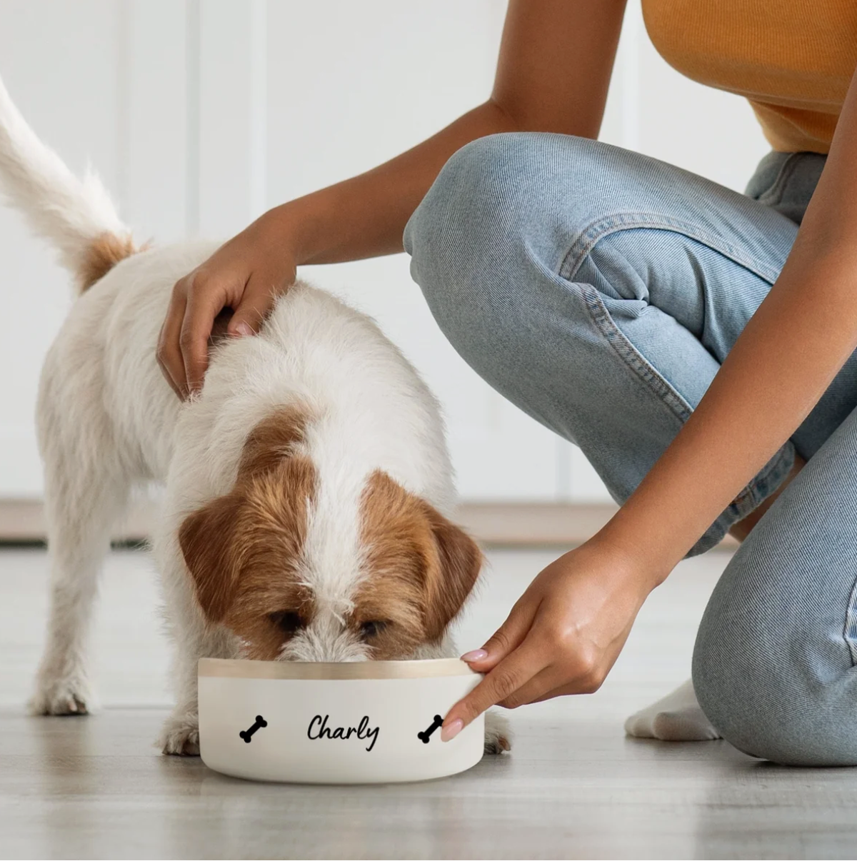 Dog eating from a personalized white bowl with the name "Charly" and bone motifs.