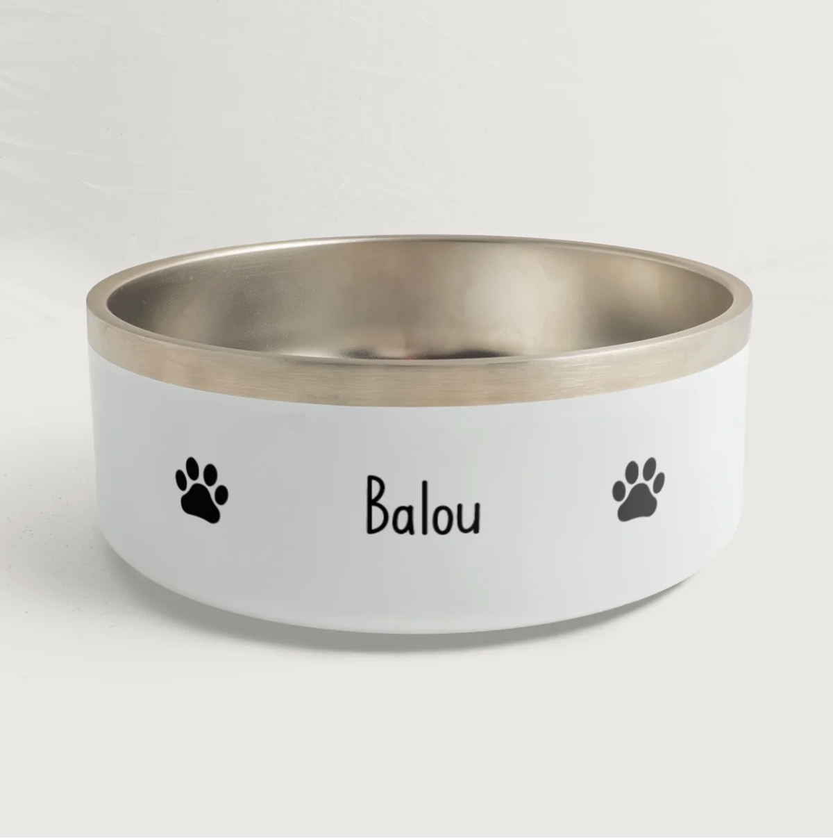 Personalized pet bowl with silver rim, the name "Balou" and black paw prints.